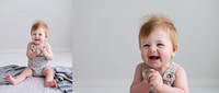 7 month old baby boy sitting on a grey rug clasping his hands and smiling