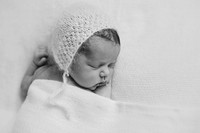 Black and white photo of a newborn baby wearing a knitted bonnet