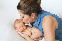 Mother kissing her newborn baby cradled in her arms