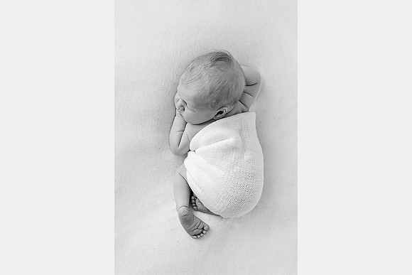 Black and white photo of a newborn baby sleeping on their tummy