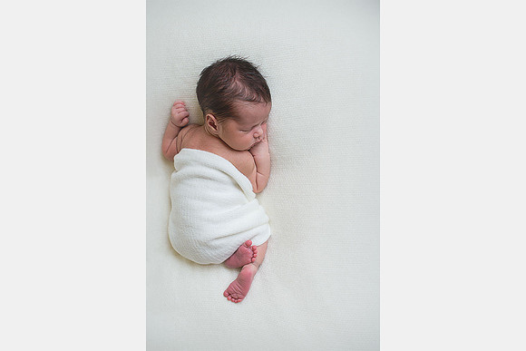 Photo looking down onto a newborn baby sleeping on a white blanket
