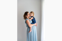 Pregnant woman kissing a little girl who sits on top her of mums pregnant belly