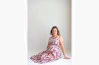 A pregnant woman sitting cradling her bump wearing a floral dress
