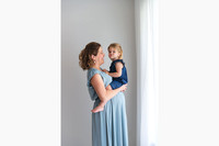 A little girl sitting on top of her mums pregnant belly making a kissy face
